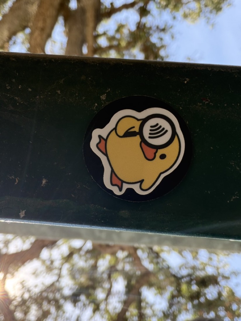 A Where the Duck tag stuck to a green park bench rail