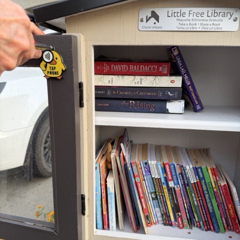 A Where the Duck tag being placed on the door of a Little Free Library