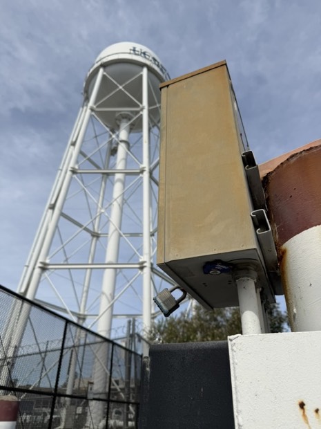A utility box beneath a water tower where a duck is hidden